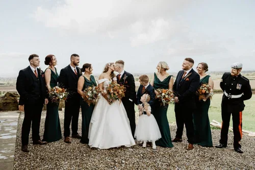 The newlyweds and their wedding party posing together outdoors.