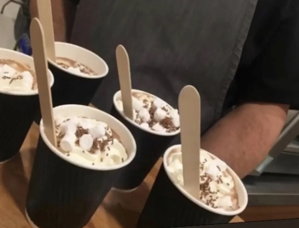 Cups of hot chocolate topped with marshmallows, ready to serve.