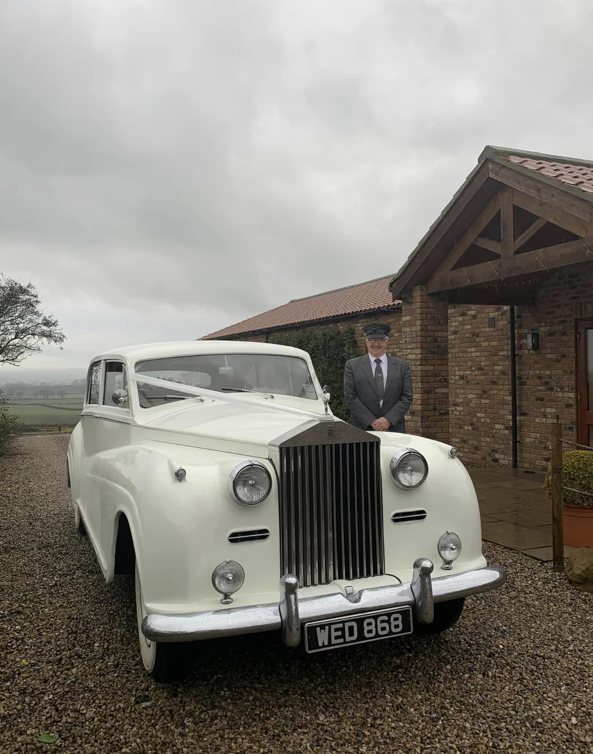 A vintage white wedding car parked outside the venue.