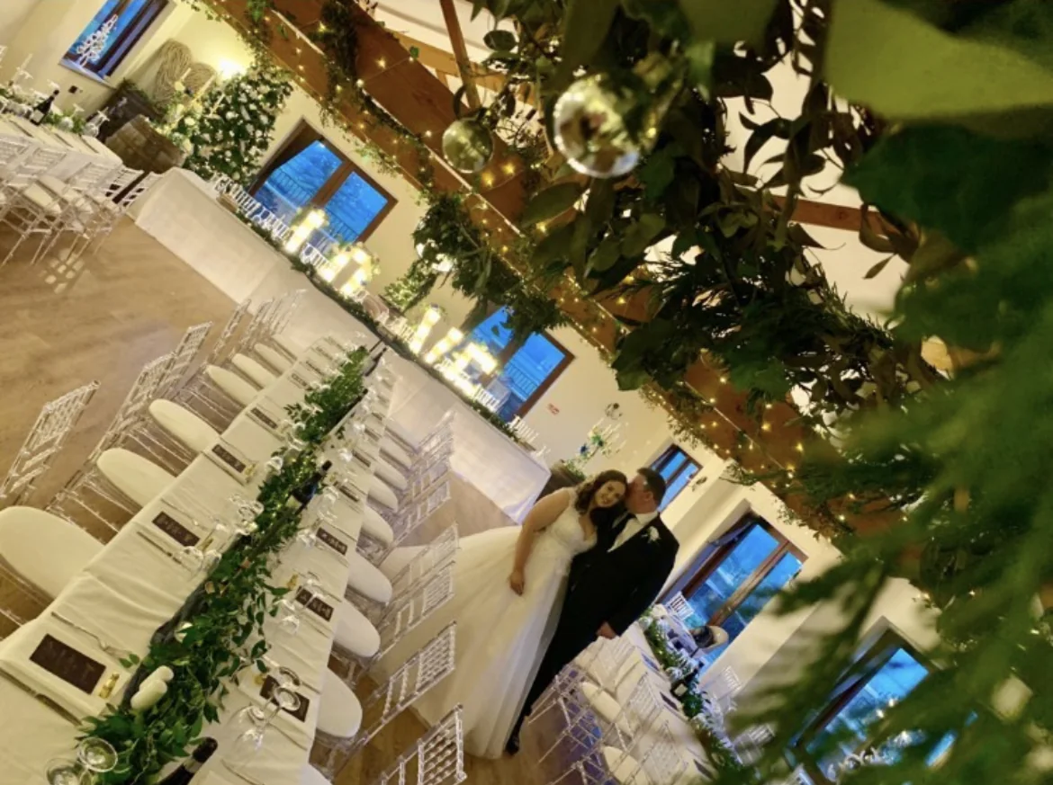 Winter wedding tables beneath greenery and hanging baubles.