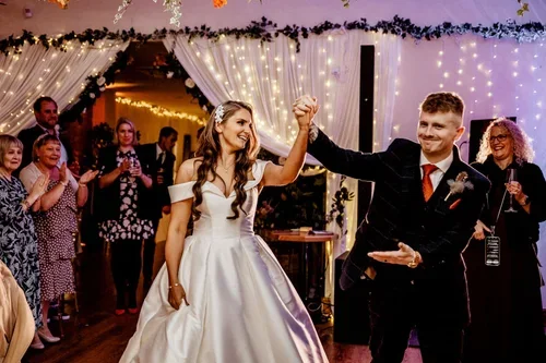 The newlyweds raising their joined hands as guests applaud.