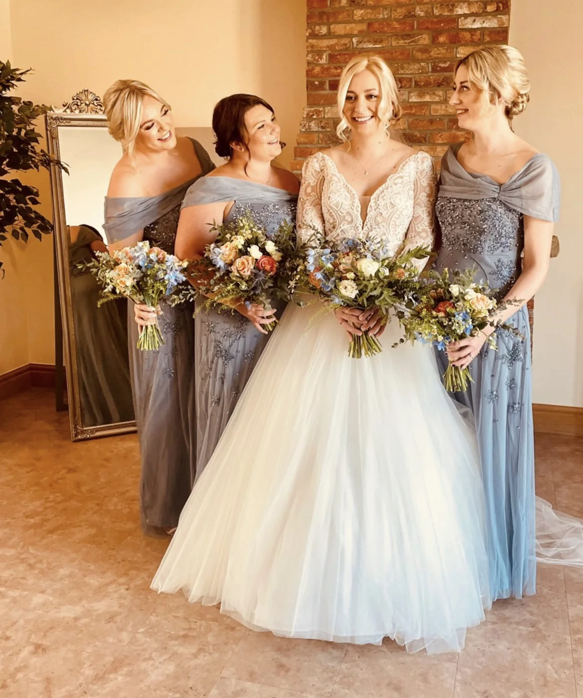 The bride and bridesmaids holding bouquets together indoors.