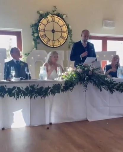 A guest speaking at the top table during the wedding reception.