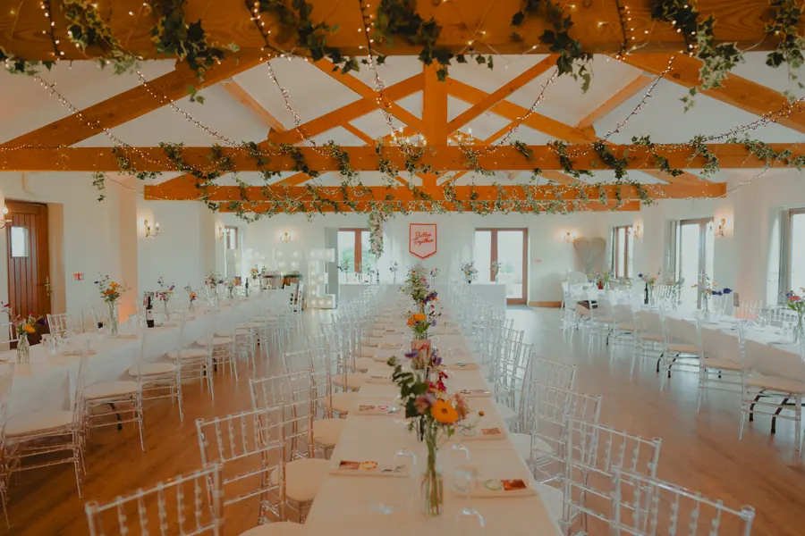 Long Hall tables beneath ivy-covered beams and multicoloured hanging fringe
