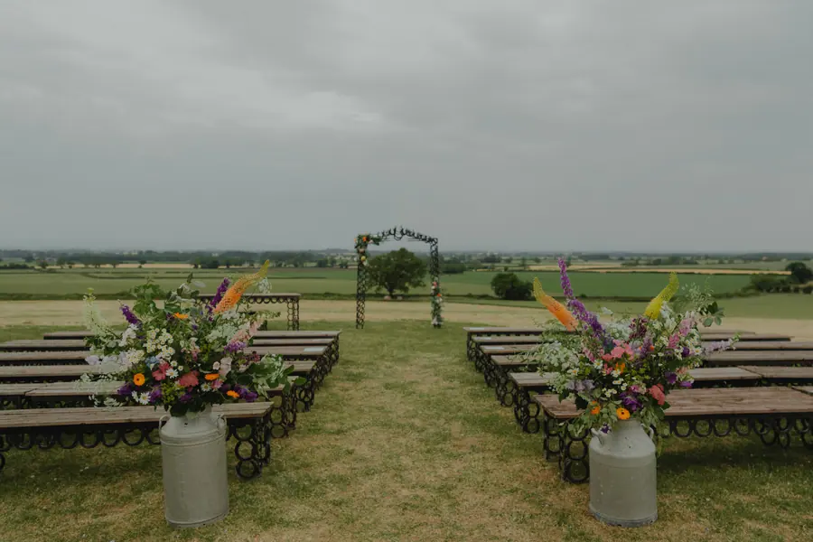 Outdoor ceremony benches facing the horseshoe arch and open fields