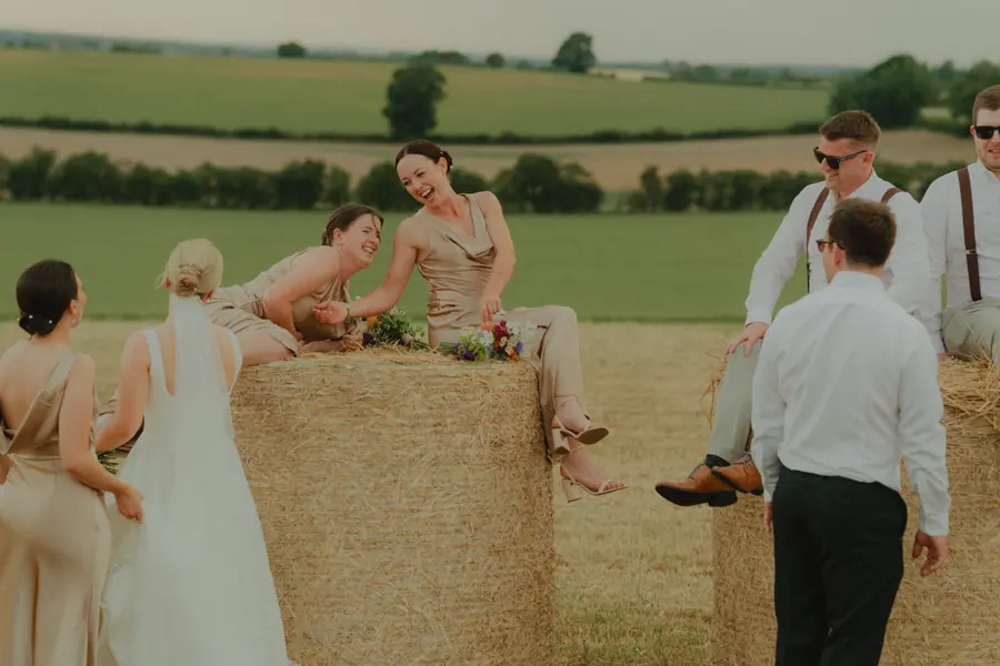 Women in rust dresses sitting on hay bales with bright bouquets
