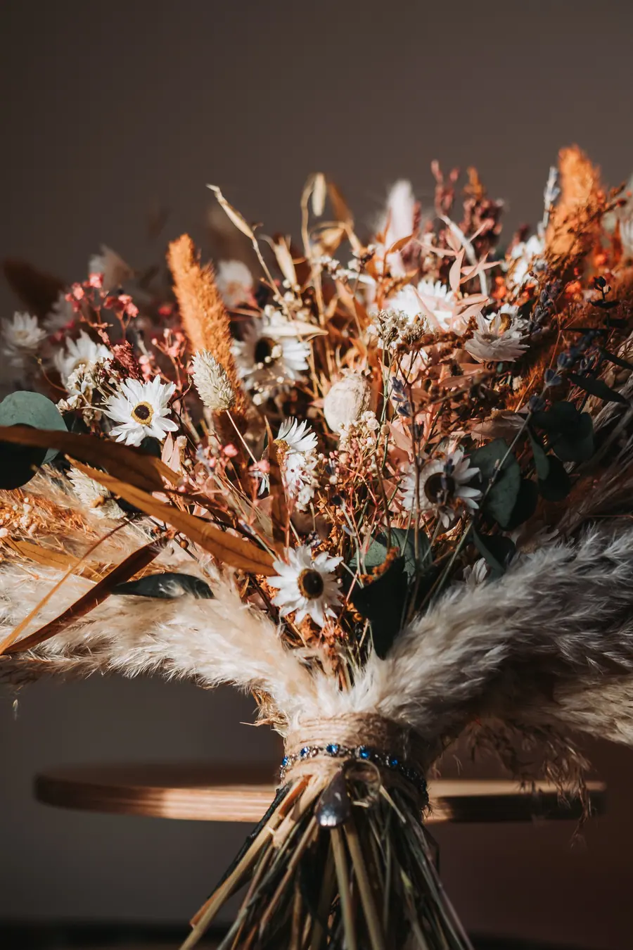 Dried white and rust flowers gathered into a loose bridal bouquet