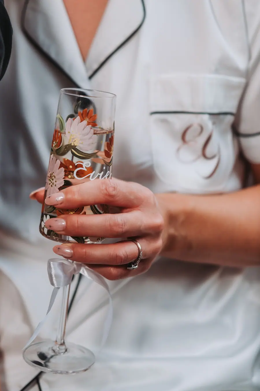Monogrammed satin robe beside a champagne flute decorated with autumn flowers