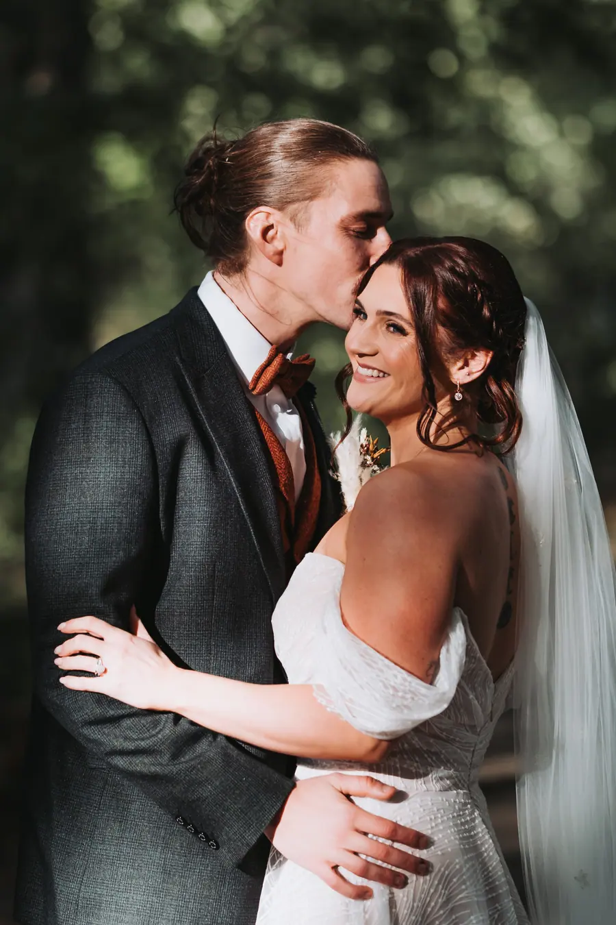 Evie-Mae and Joe standing close together beneath leafy garden trees