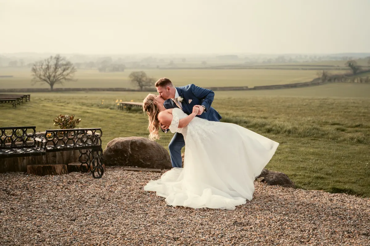 Jayrrd dipping Hayley on gravel with open fields behind them