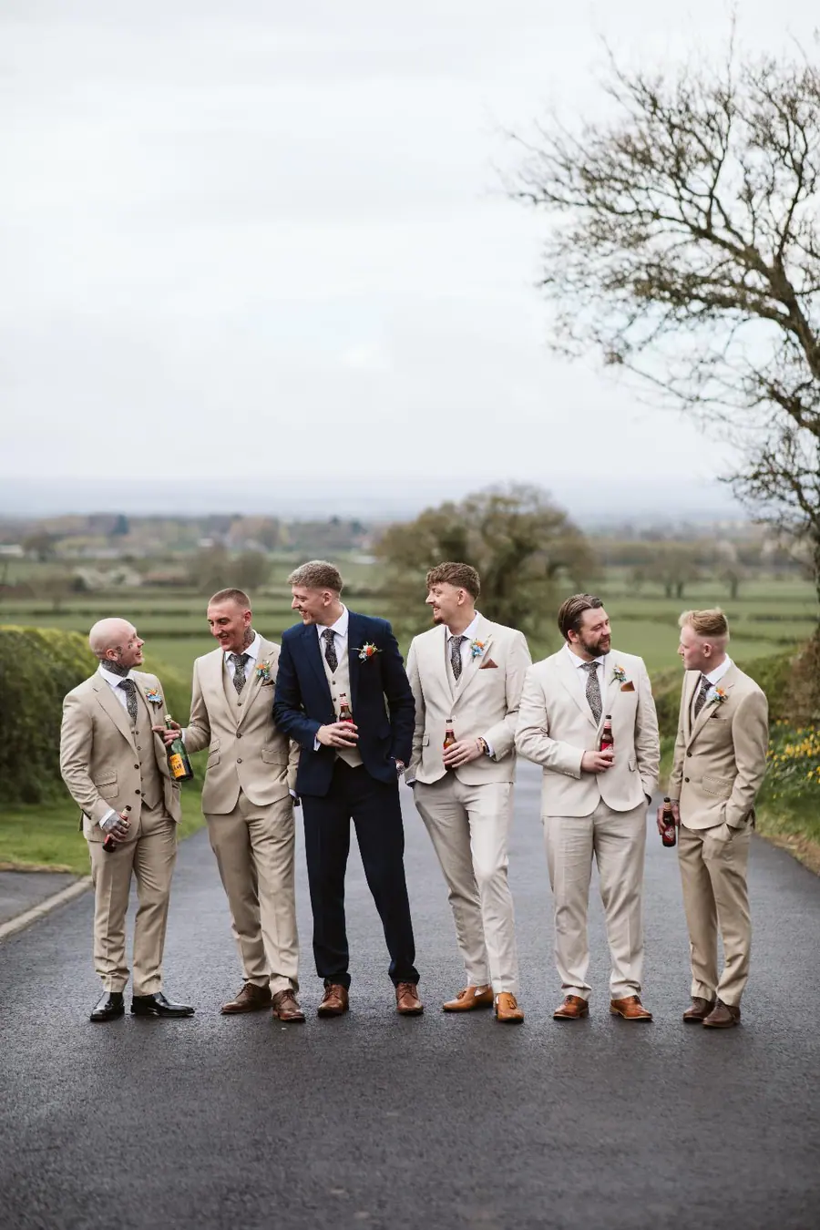 Jack with six groomsmen lined along the lane above the fields