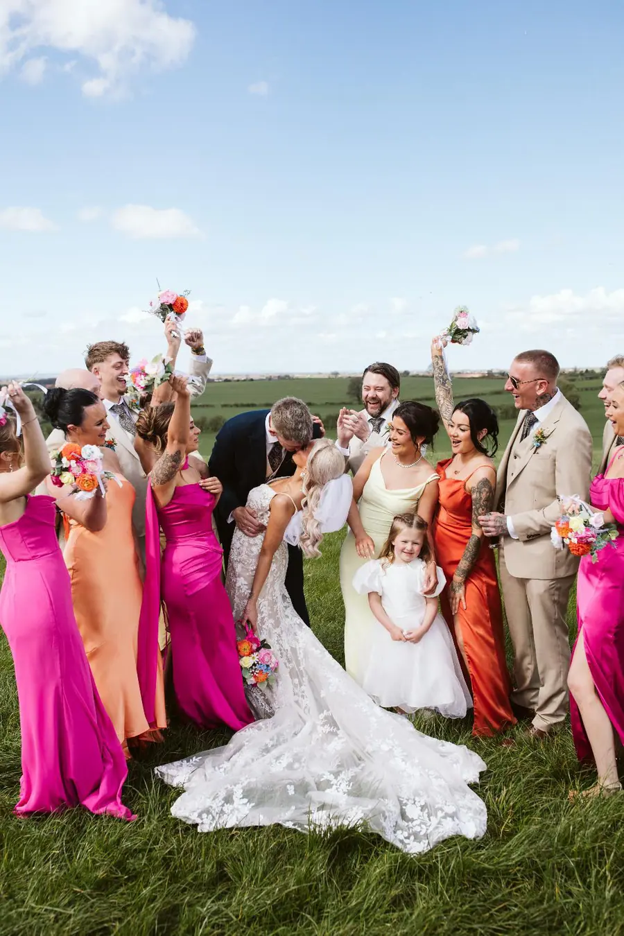 The couple surrounded by their wedding party in bright pink and orange