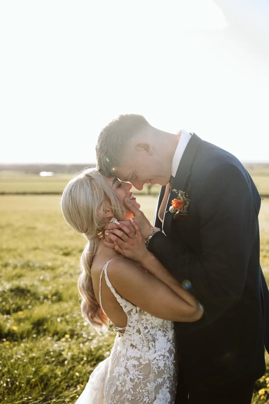 Jack and Harriet kissing in low sunlight beside the open fields
