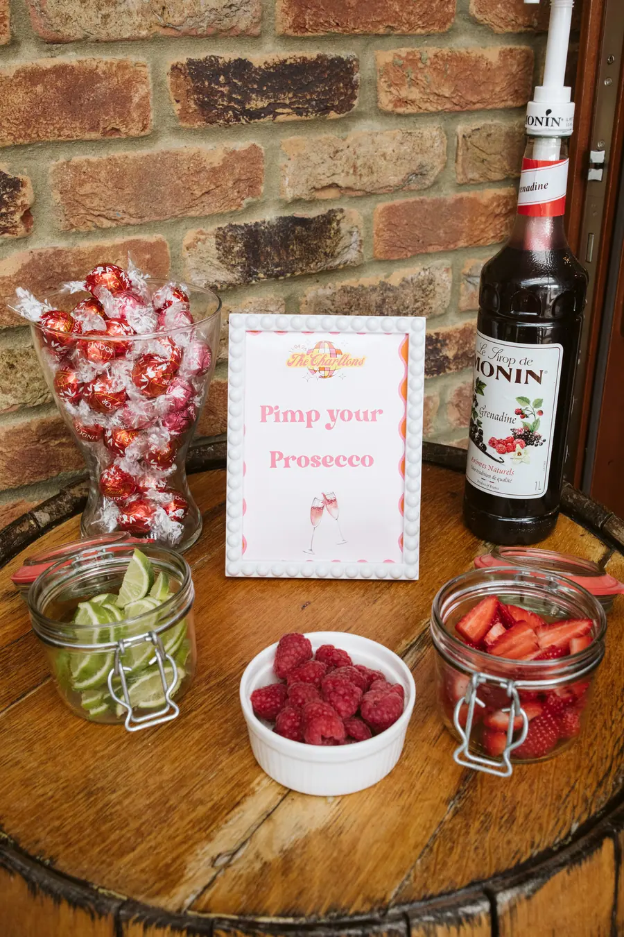 Make-your-own prosecco display with fruit jars and a bottle on a barrel