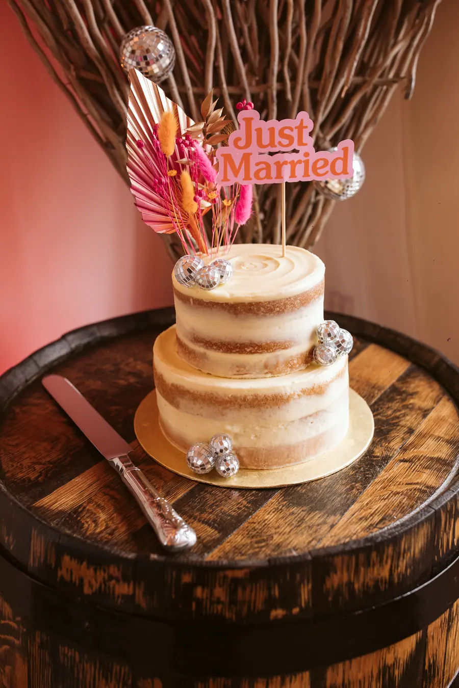 Small tiered wedding cake with a Just Married topper on a barrel