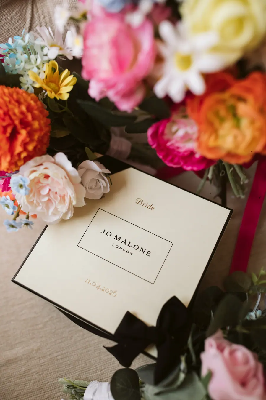 Pink and orange flowers beside a Jo Malone card and place setting