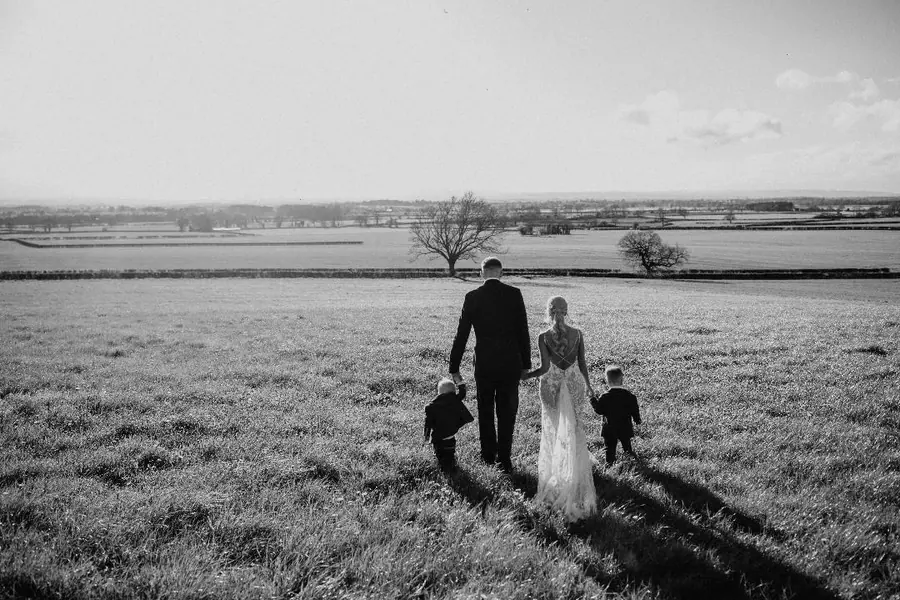 The couple and two children walking across the field at sunset