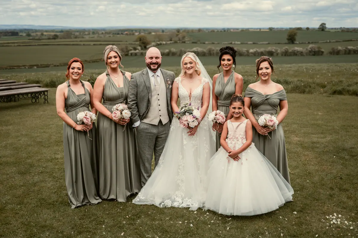 Katie and Chris with five attendants and a young girl outdoors