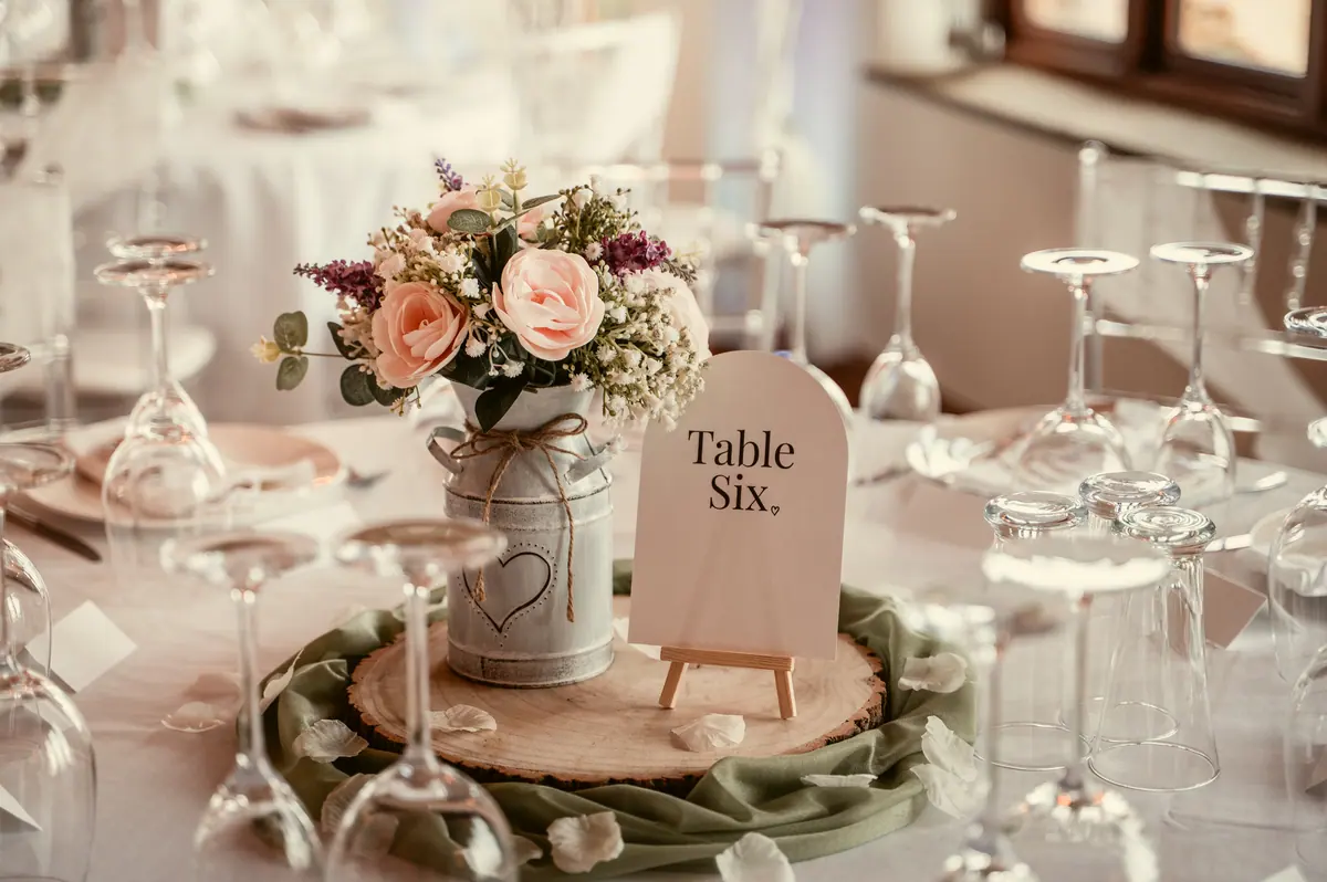 Small pink flower arrangement beside green napkins and clear table glassware
