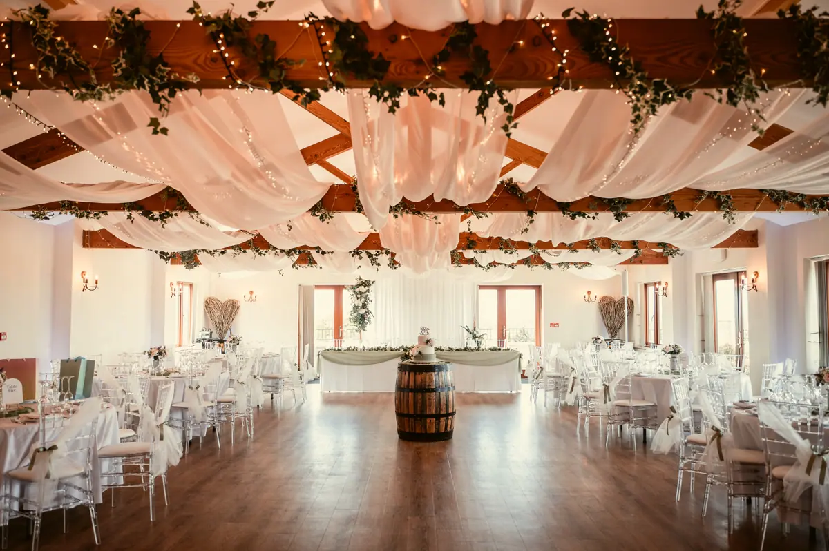 Round Hall tables beneath white drapes, greenery and warm ceiling lights