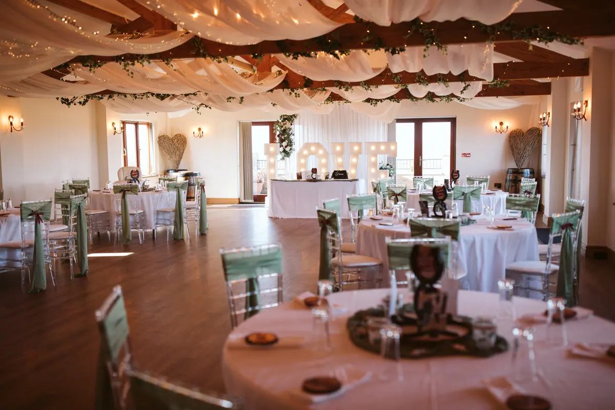 Round Hall tables arranged beneath white drapes and wooden beams