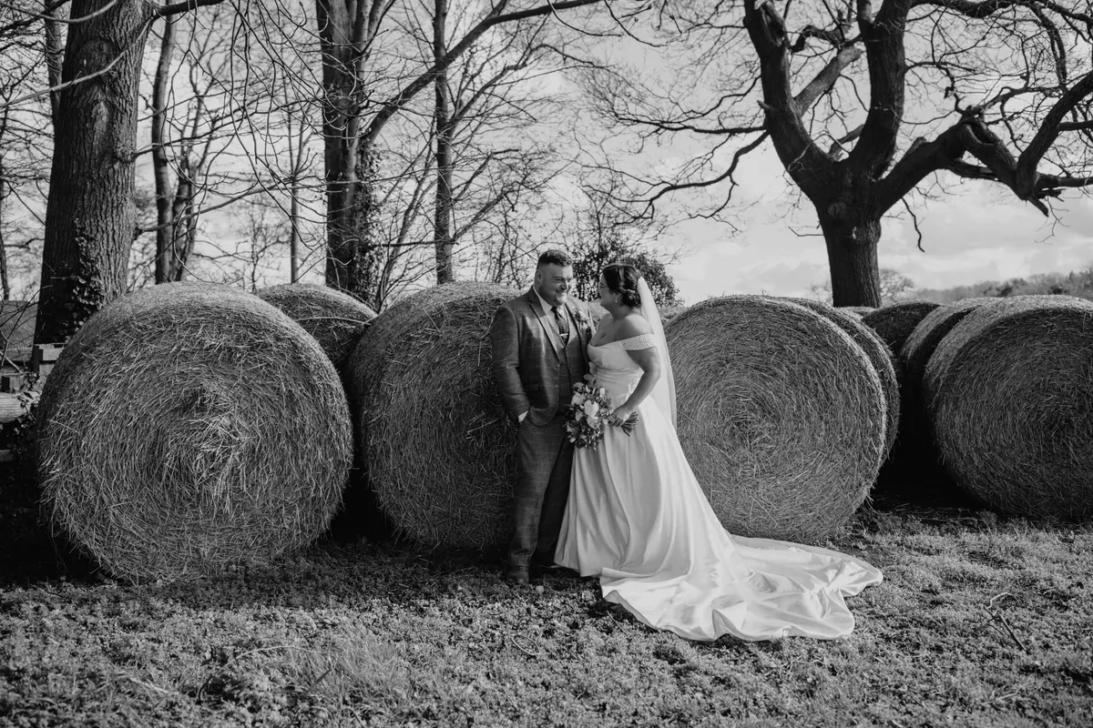 Katy and George beside hay bales in a black and white view