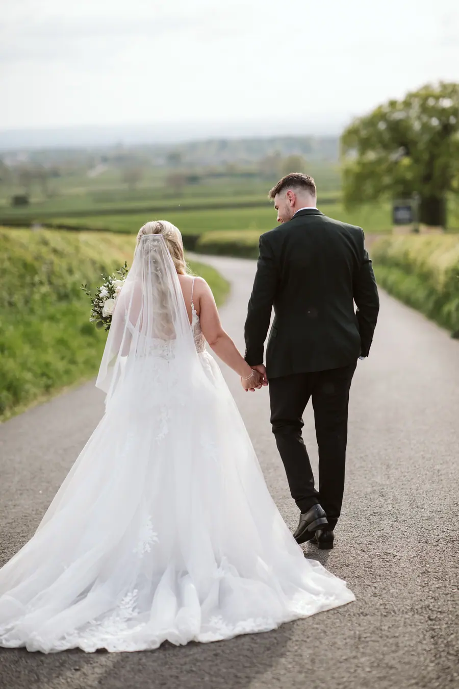 The couple walking away hand in hand with Lauren's train across the lane