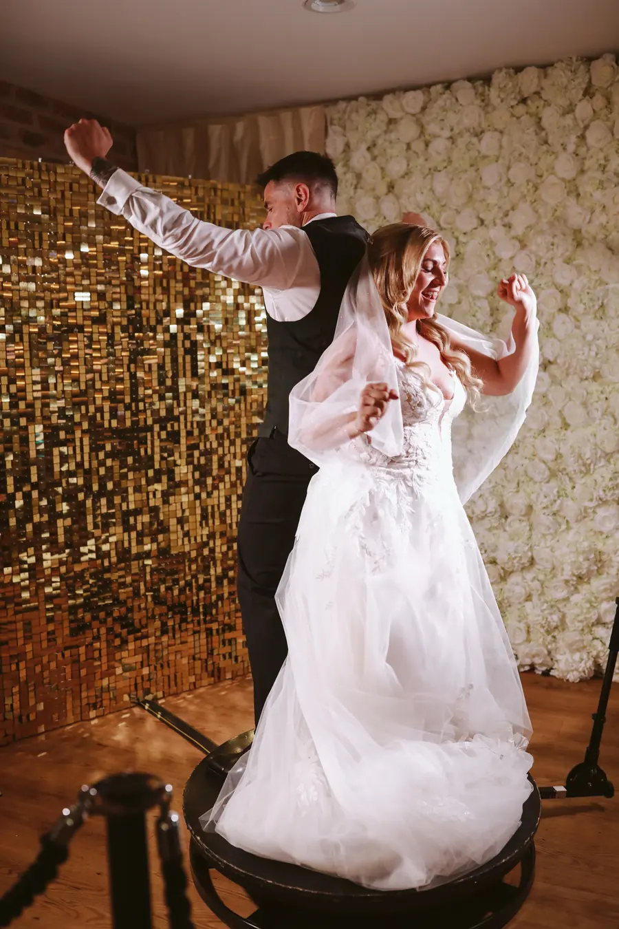 Lauren and Iain dancing on a round platform before a gold wall