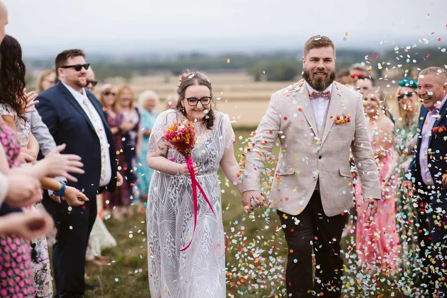 Confetti falling across Lauren and Martin as they leave the outdoor ceremony
