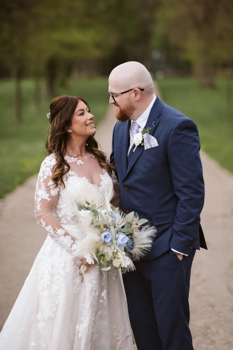 The couple facing each other with Lisa's pale blue and white bouquet