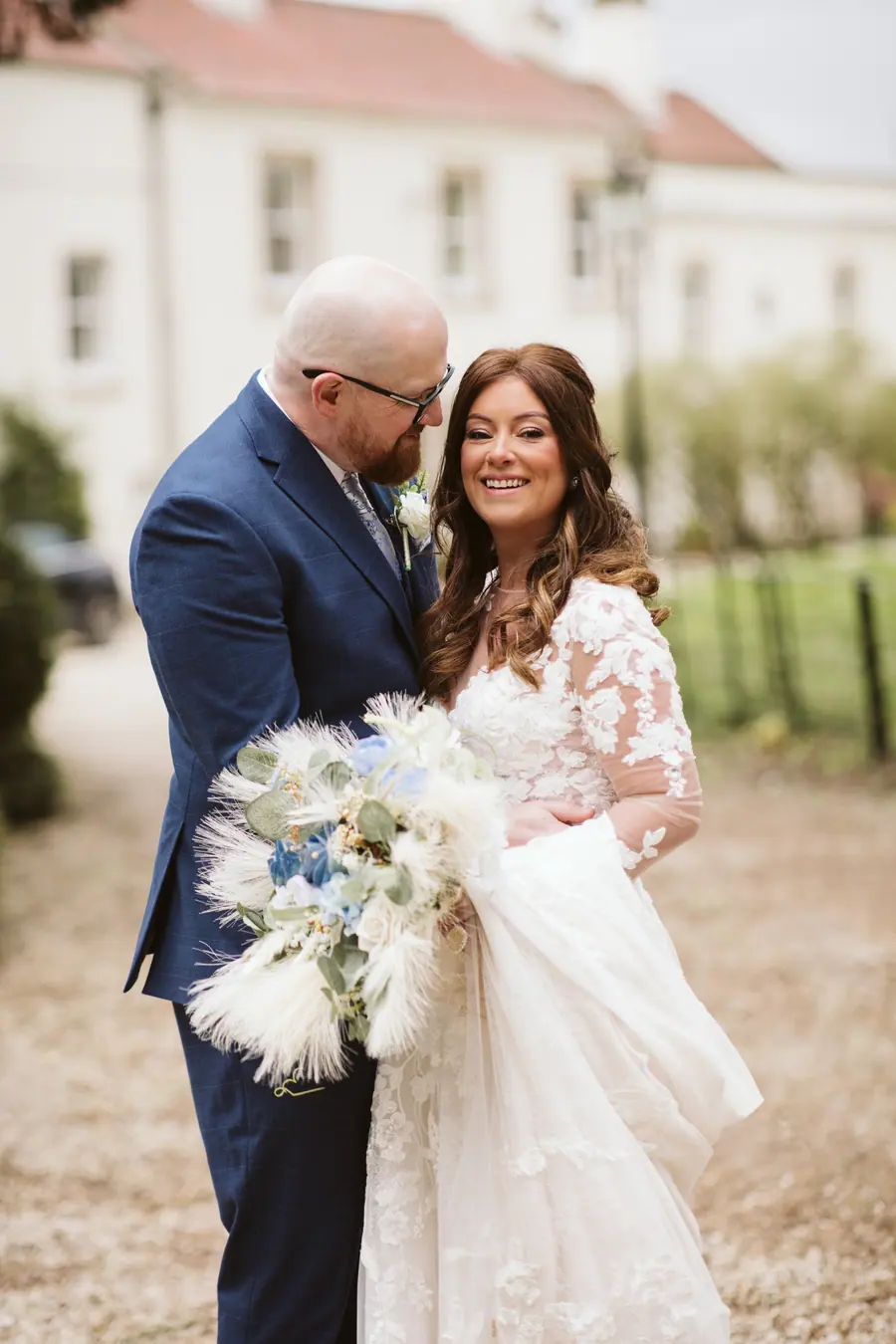 Dean holding Lisa beside the brick barns and gravel courtyard