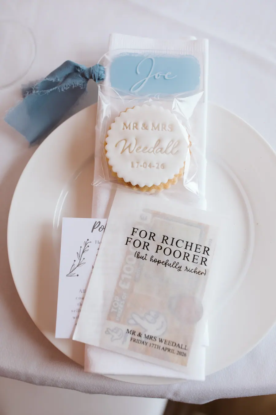 Printed wedding favour and pale blue napkin arranged on a white plate