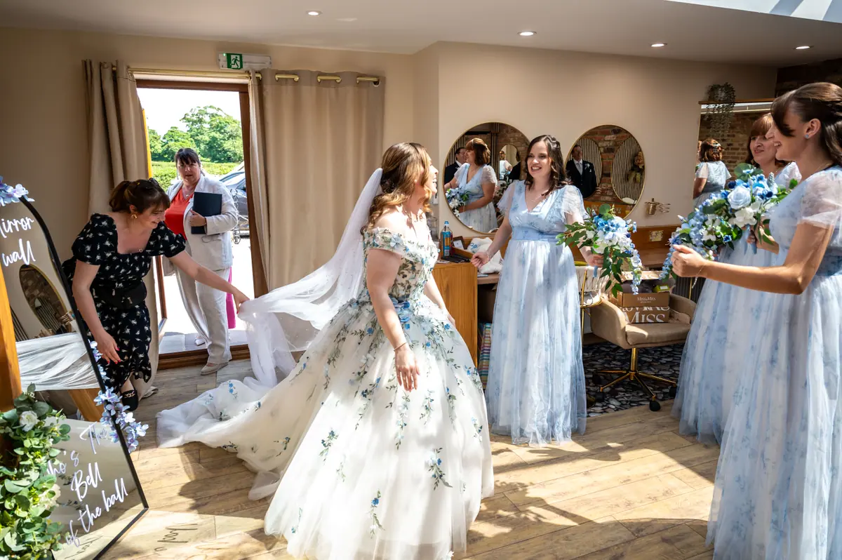Megan standing in sunlight among women carrying blue and white bouquets