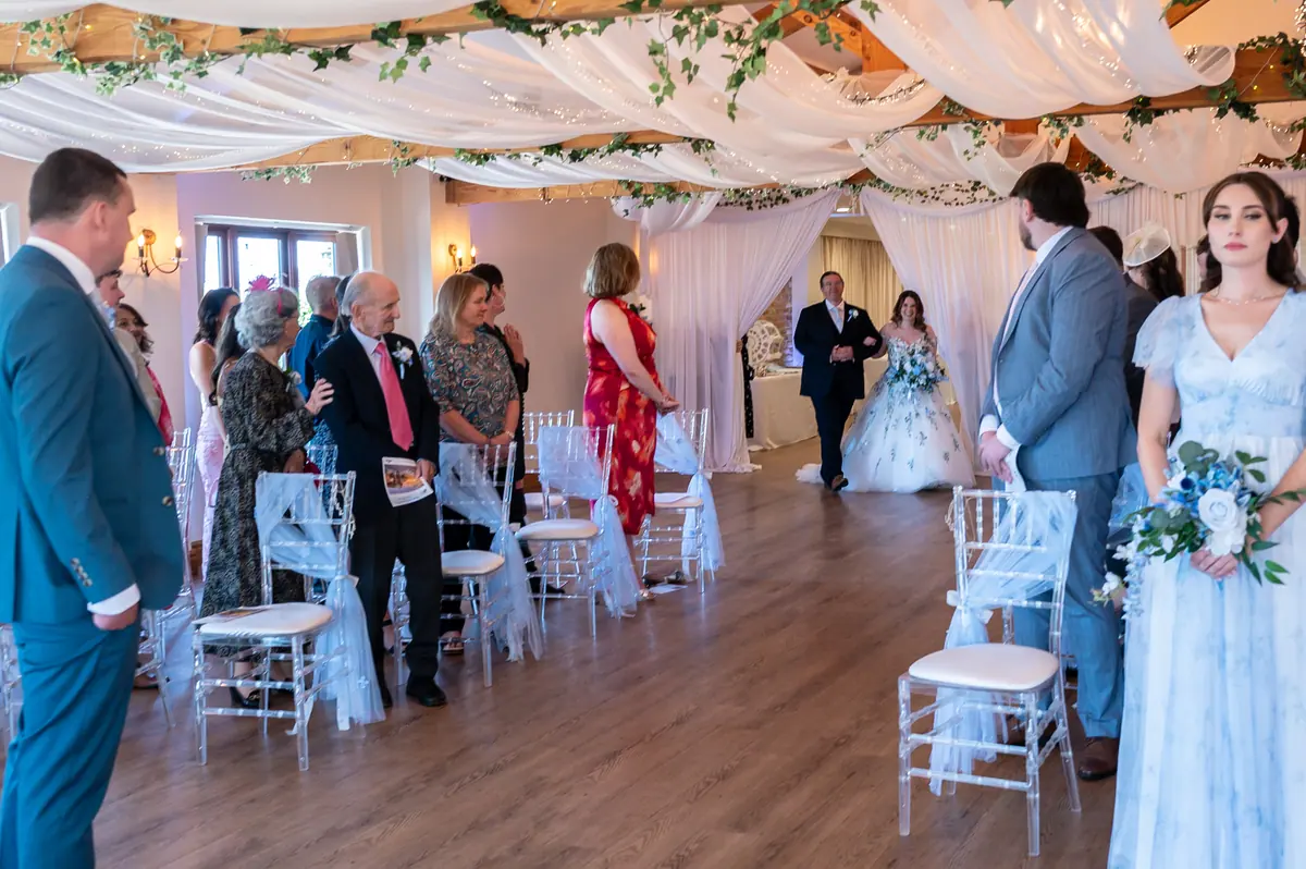 Megan walking between clear chairs towards Dan inside the Hall