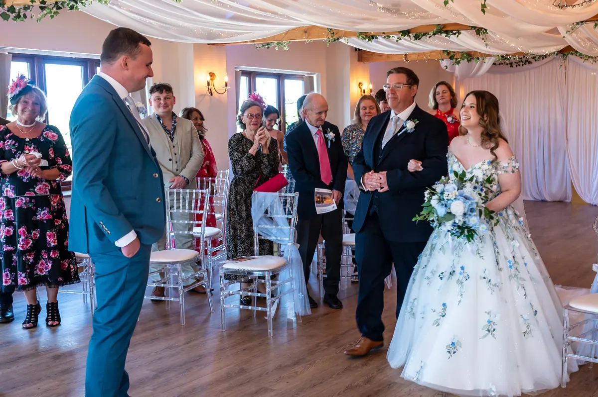 Megan reaching Dan at the end of the indoor ceremony aisle