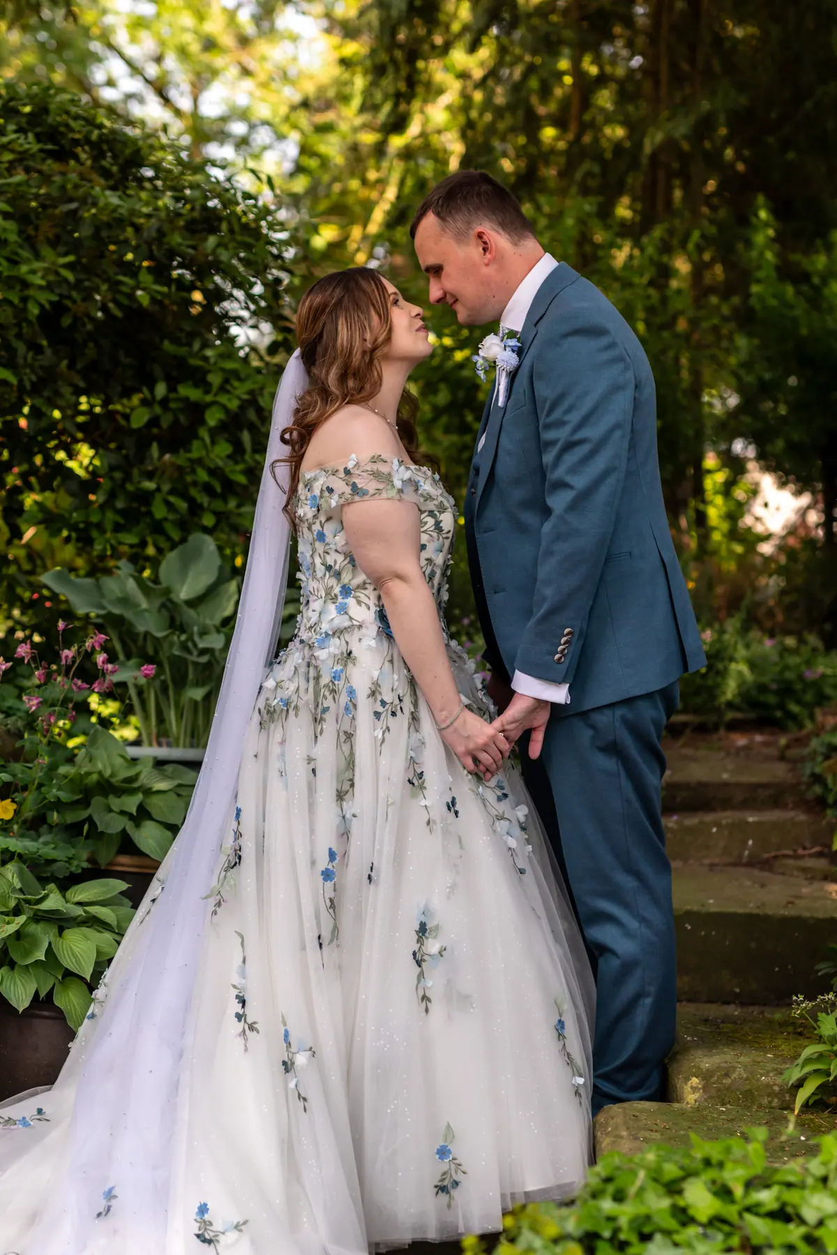 The couple embracing in a shaded garden surrounded by green foliage