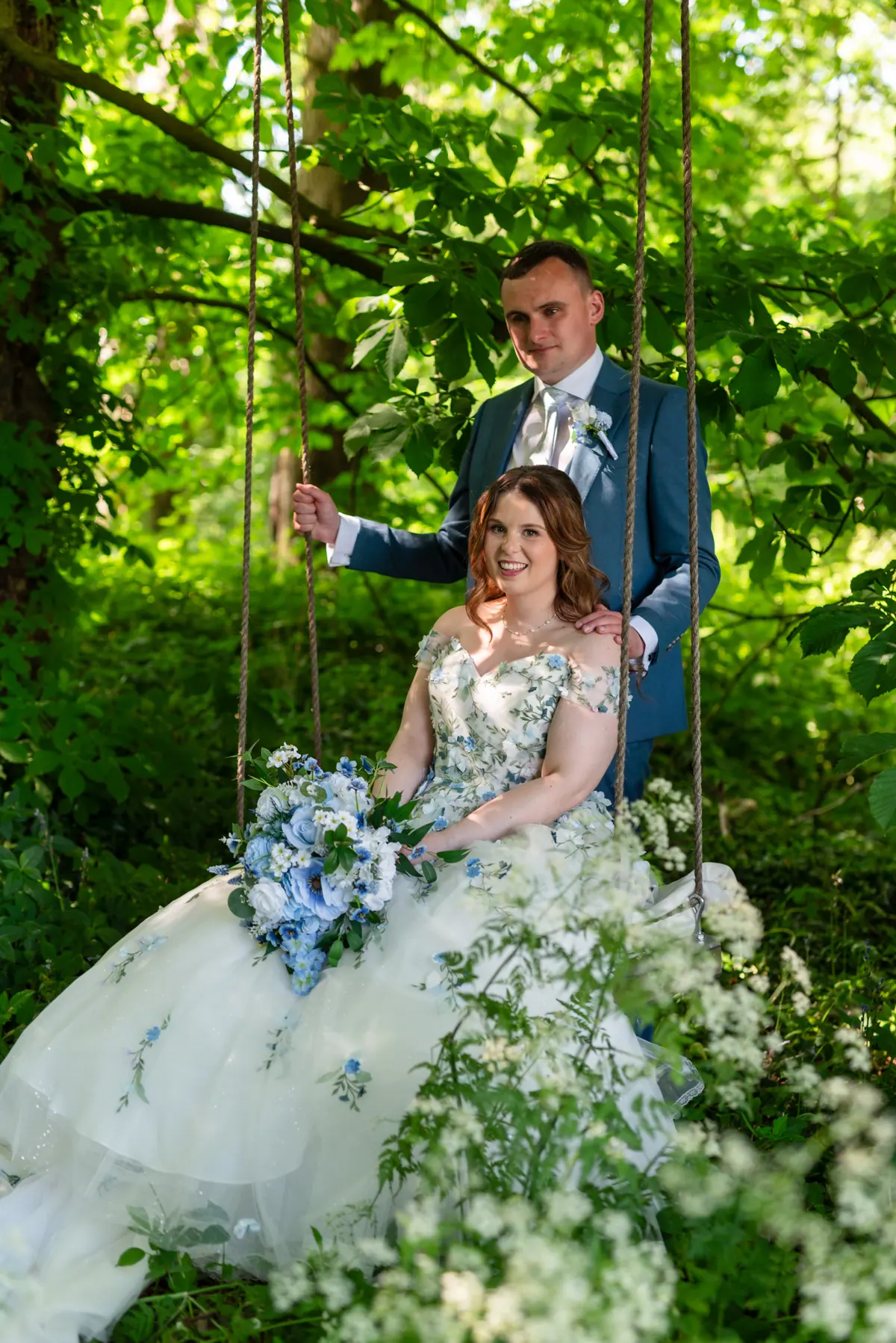 Megan seated among white flowers while Dan stands beside her
