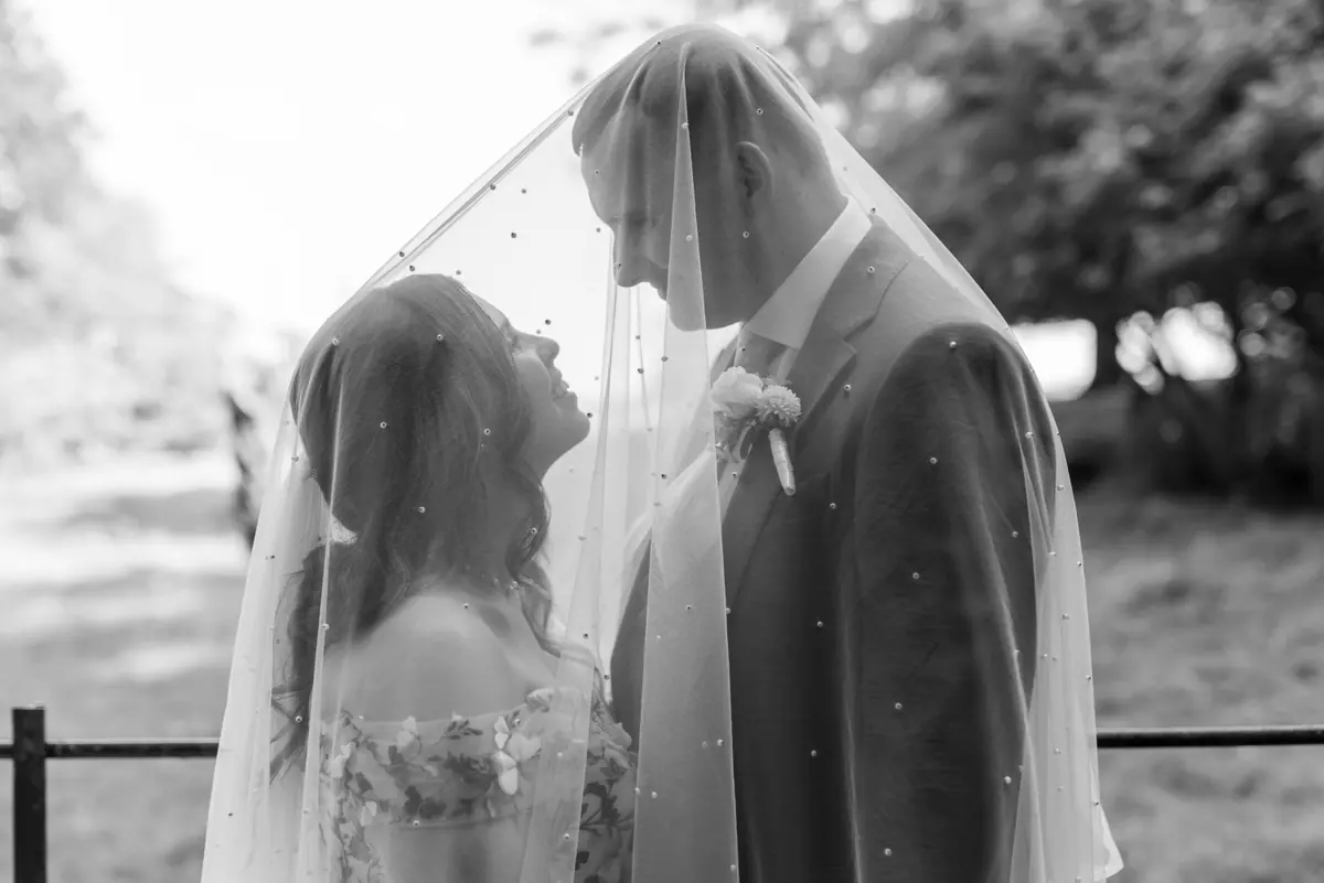 The couple kissing beneath Megan's veil in a monochrome close view