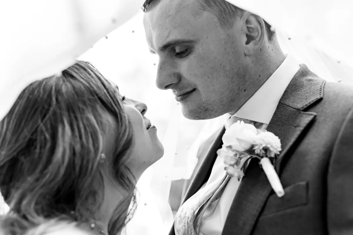 Close black and white view of Dan above Megan's floral shoulder