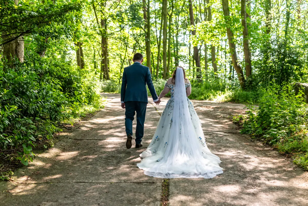 Megan and Dan walking away together along a sunlit woodland path