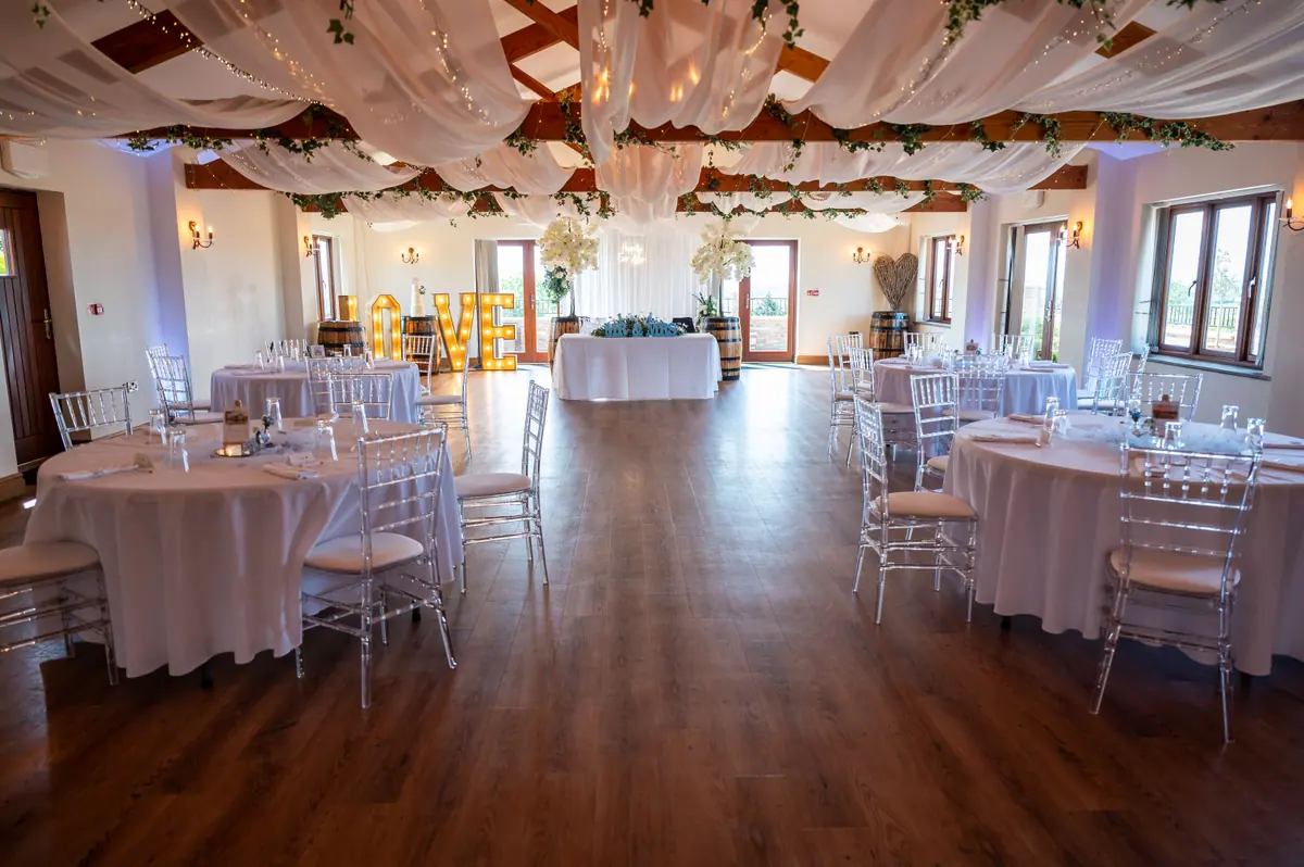 Round tables and clear chairs arranged across the dressed Hall