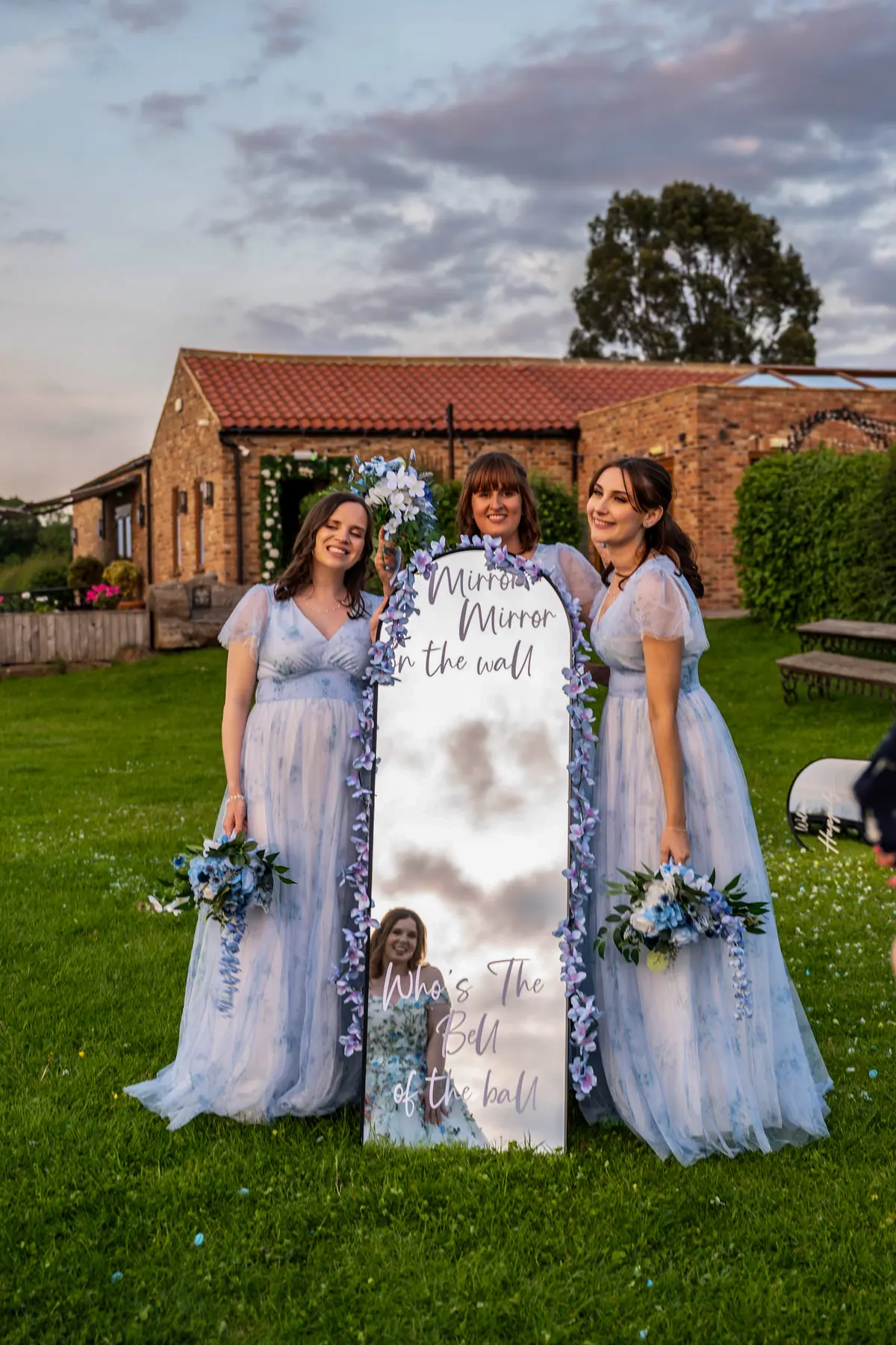 Megan with two women holding a memorial sign and flowers outdoors