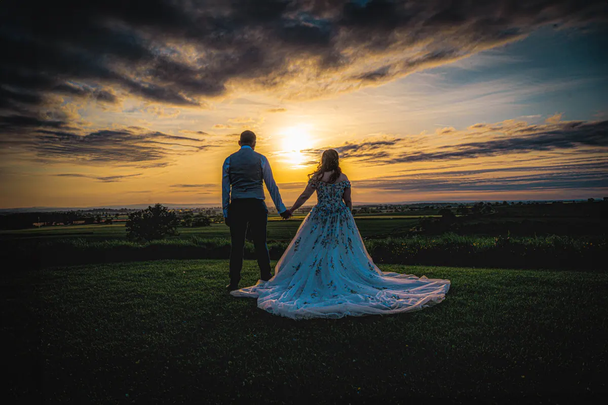 Megan and Dan holding hands in silhouette against a bright sunset