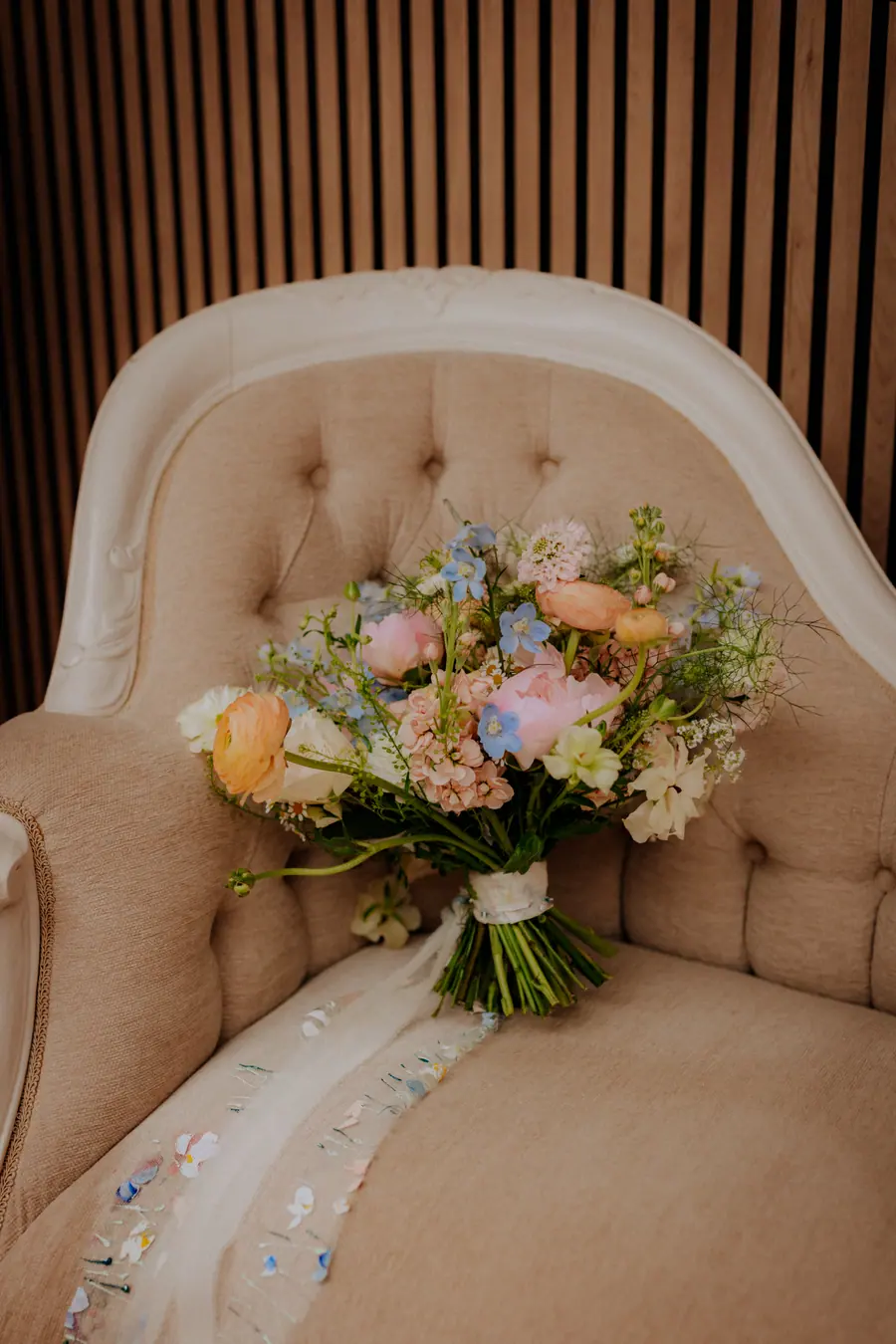 Peach, pink and white bridal bouquet resting on a cream chair