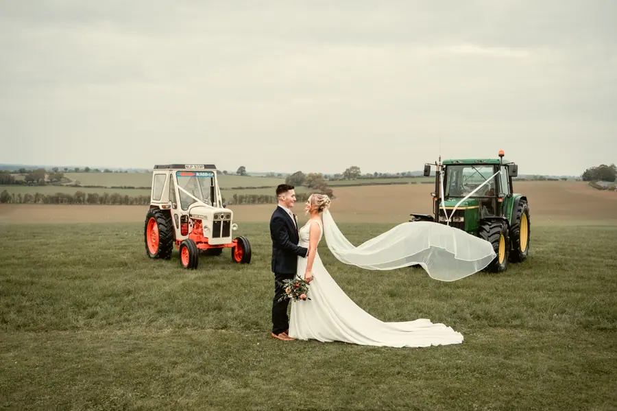 The couple walking across the field between two parked tractors