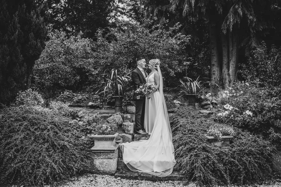 Olivia standing alone on stone steps among trees in black and white