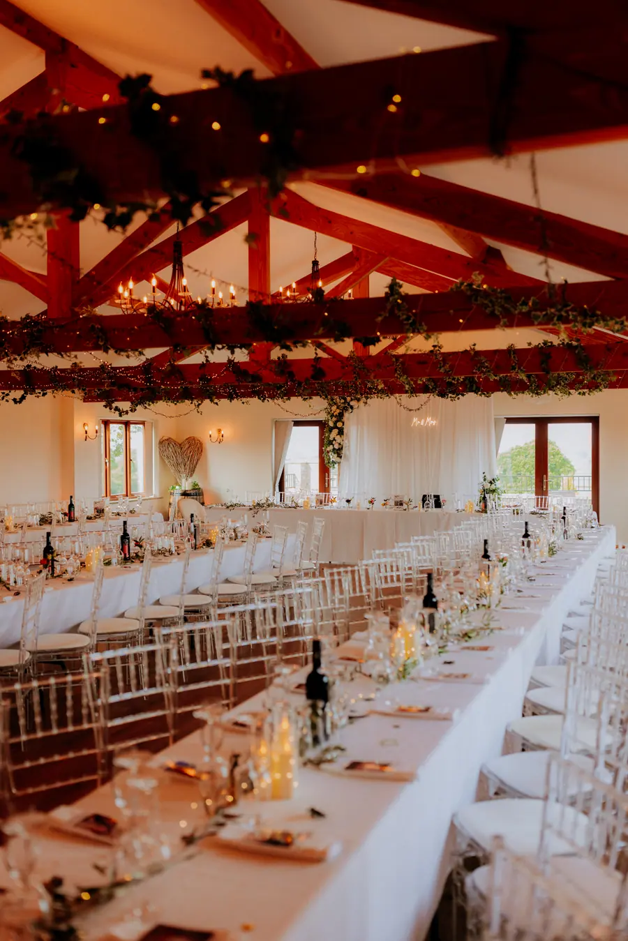 Long Hall table laid with clear chairs, candles and small flowers