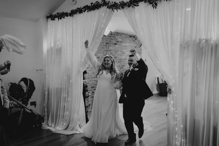 Olivia and Luke entering the Hall together between tall white drapes