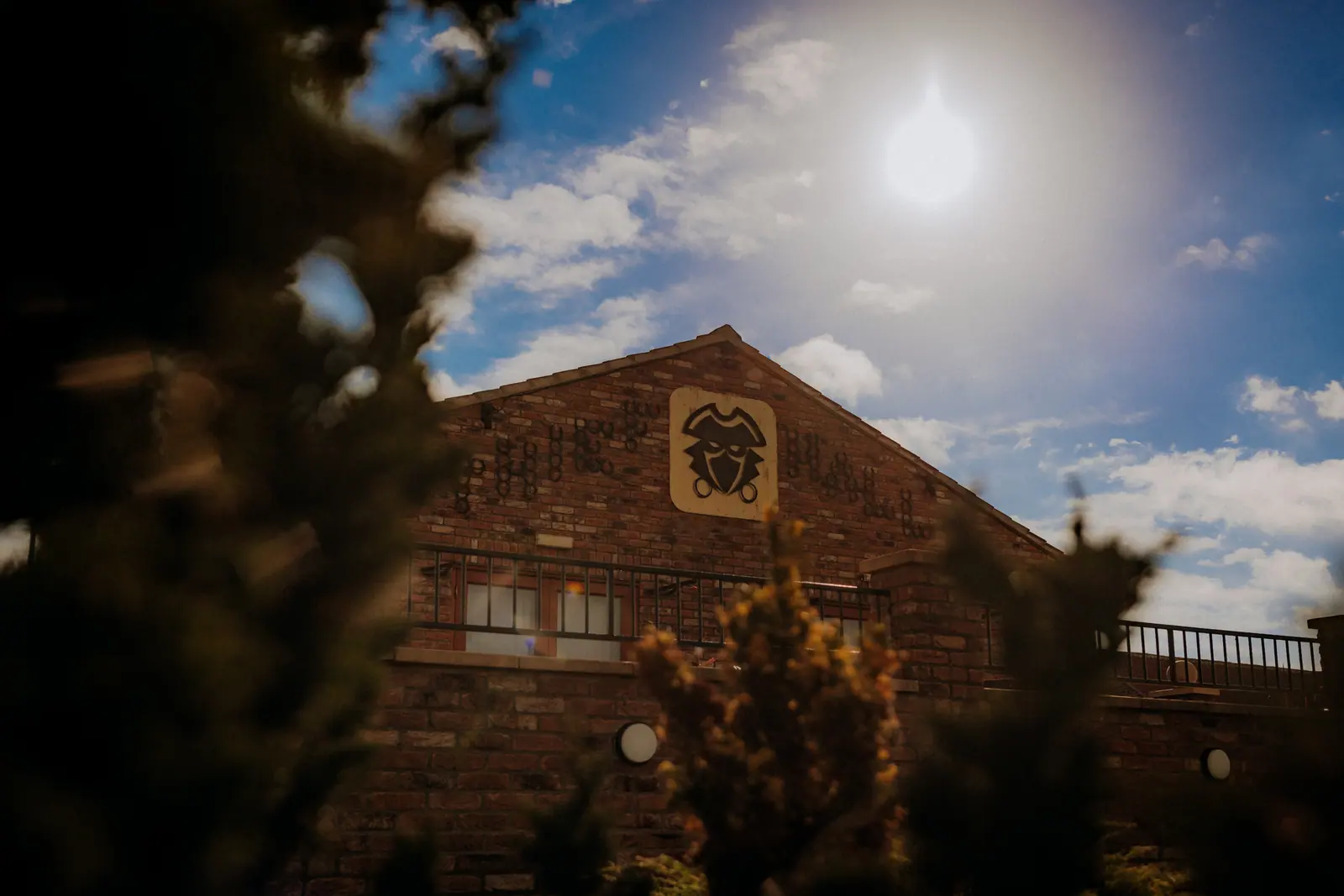 Thief Hall barn front beneath bright sun and a deep blue sky