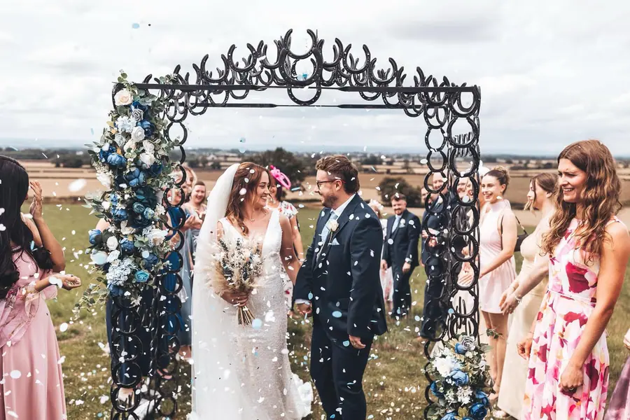 Confetti falling around Sophie and Jake as they leave the outdoor ceremony
